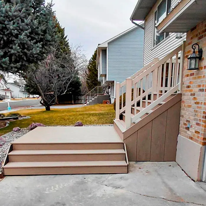 Completed grey composite deck and entry stairs installation with white vinyl railings in Rexburg, ID.