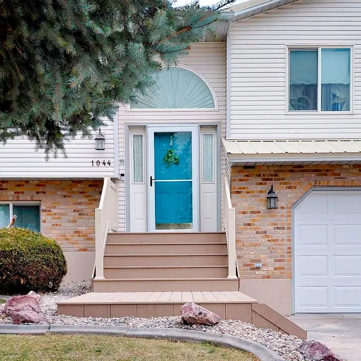 A spacious, ground-level brown composite deck featuring a large white permanent roof structure and black metal perimeter railings.
