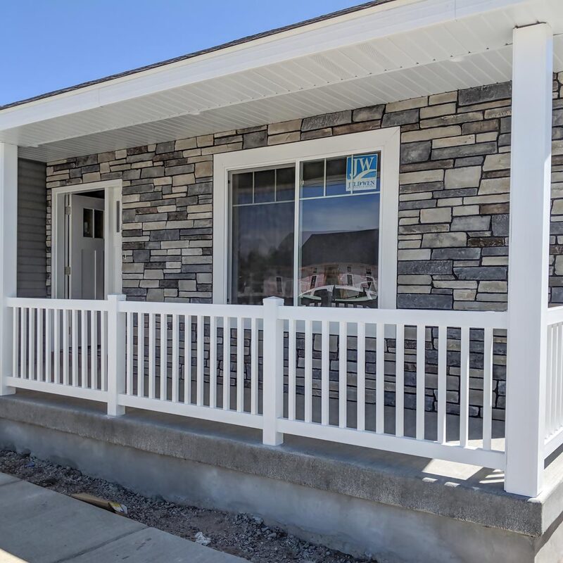Elevate your home's curb appeal with a durable and low-maintenance vinyl railing system. This project features a classic white vinyl railing with vertical balusters, perfectly complementing the modern stone veneer facade. The sturdy white vinyl columns provide essential support for the porch overhang while matching the sleek railing, creating a unified and inviting entrance.