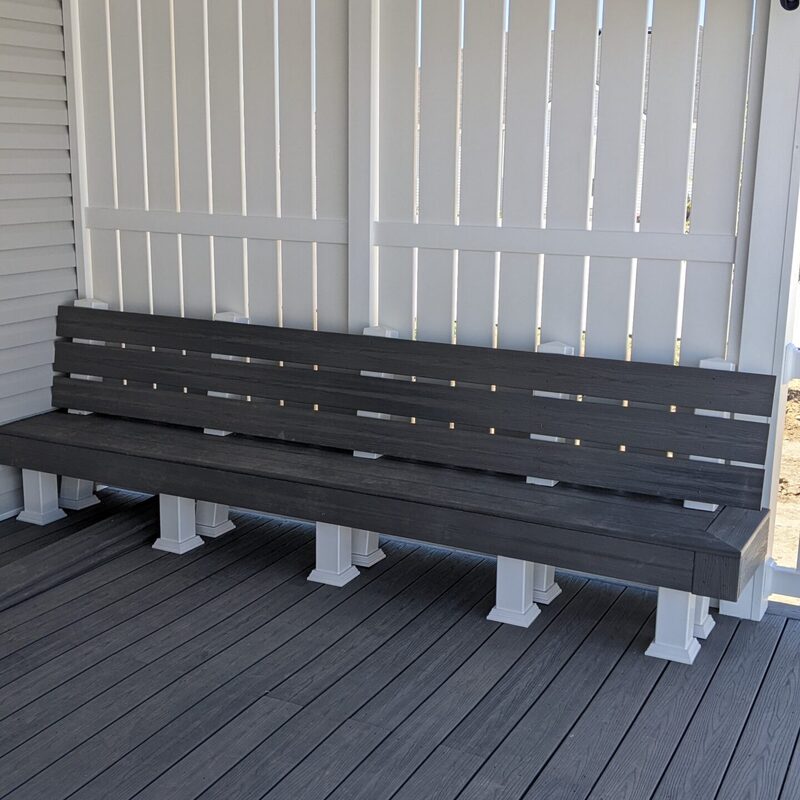 Expand your outdoor living possibilities with this custom deck by DeckPro LLC, which combines functional seating with elegant privacy. We installed low-maintenance composite decking in a modern grey tone and paired it with a unique built-in bench featuring matching grey slats and contrasting white support posts. For the ultimate in functional design, we included a stylish white vertical louvered privacy wall, creating a cozy and inviting retreat.