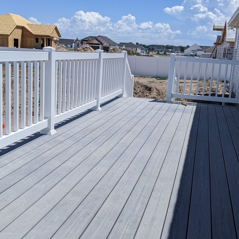 Expand your outdoor living possibilities with this custom composite deck by DeckPro LLC. This design provides a safe and stylish transition from your home to your backyard, even in snowy conditions, thanks to durable, low-maintenance composite materials. We included a unique railing system that combines clean white posts with a striking horizontal louvered privacy wall on one end, creating a cozy and inviting retreat.