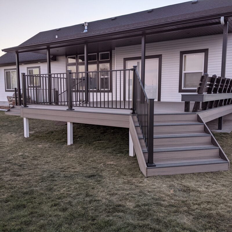 Enjoy outdoor living rain or shine with this versatile covered composite deck by DeckPro LLC. The design features a custom built-in bench for ample seating and sleek black metal railing for a modern finish.