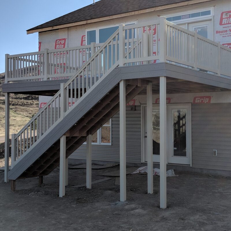 Expand your living space outdoors with a custom second-story deck from DeckPro LLC. This new construction project features durable grey composite decking paired with classic white vinyl railing, providing a safe and stylish elevated retreat with easy access to the yard below via a long staircase.