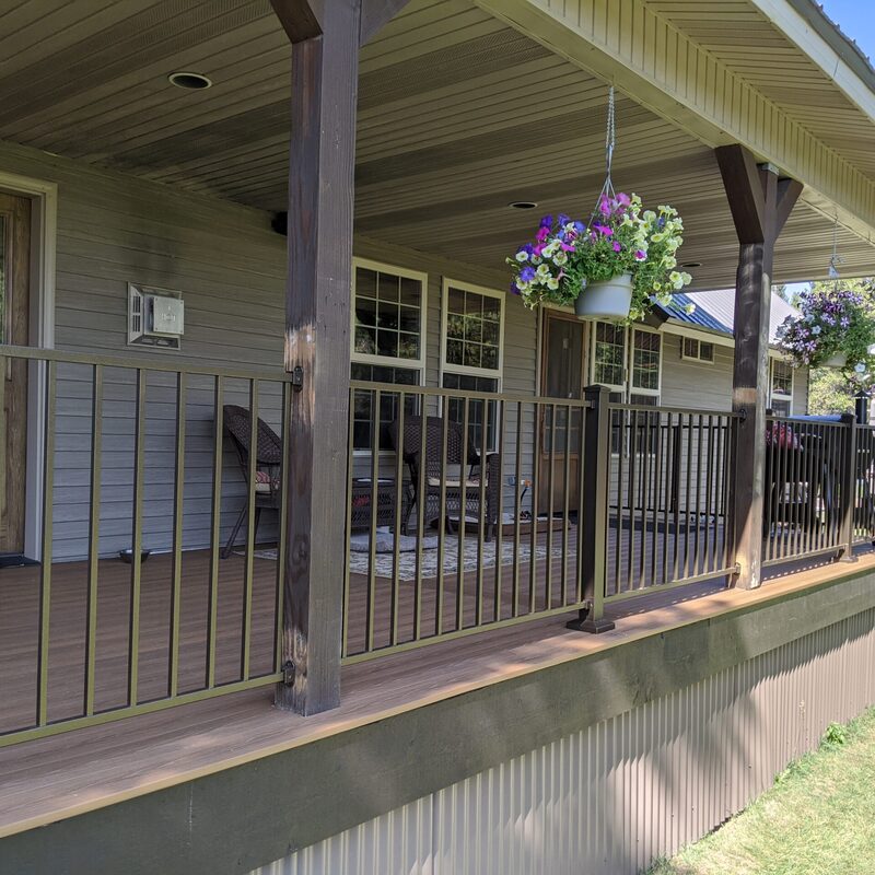 Enhance your home's curb appeal with this massive and inviting custom covered front porch by DeckPro LLC. This wide-span installation transforms the front of a country-style home with grey siding into a beautiful, low-maintenance retreat. Featuring premium wood-grain textured composite decking planks in a rich, warm brown tone, this porch offers years of worry-free relaxation.