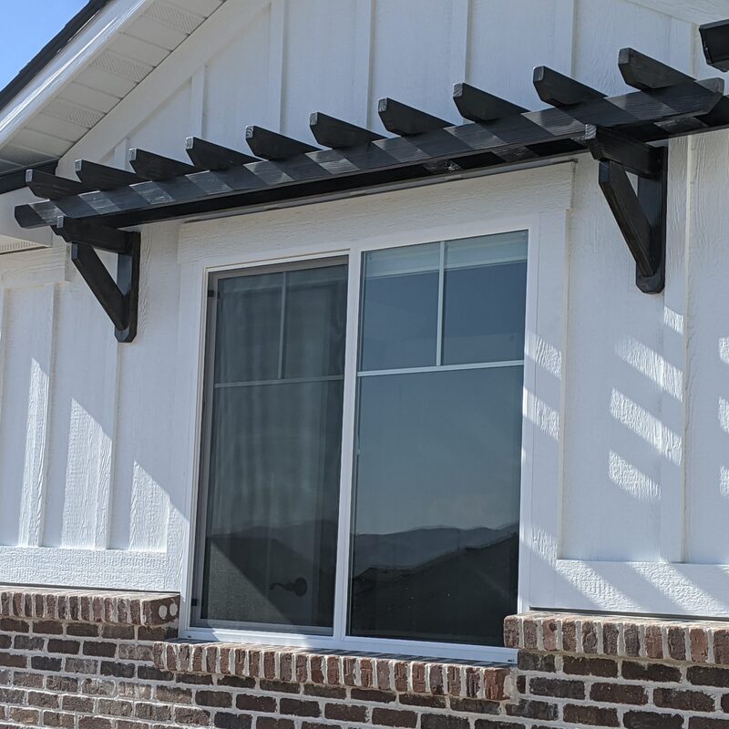 Expand your outdoor living space with this cozy raised deck by DeckPro LLC. We installed high-quality, low-maintenance composite decking in a warm brown tone and paired it with safe and sophisticated dark vertical perimeter railings, creating a sturdy retreat perfect for relaxation. Pictured on a beautiful sunny day with clear skies and distinct shadows cast across the deck boards, this functional build transitions through a massive and inviting set of stairs leading to a stamped concrete patio, creating defined sun and shade areas and optimizing views of the vast backyard. Direct access is available via a sliding glass door.