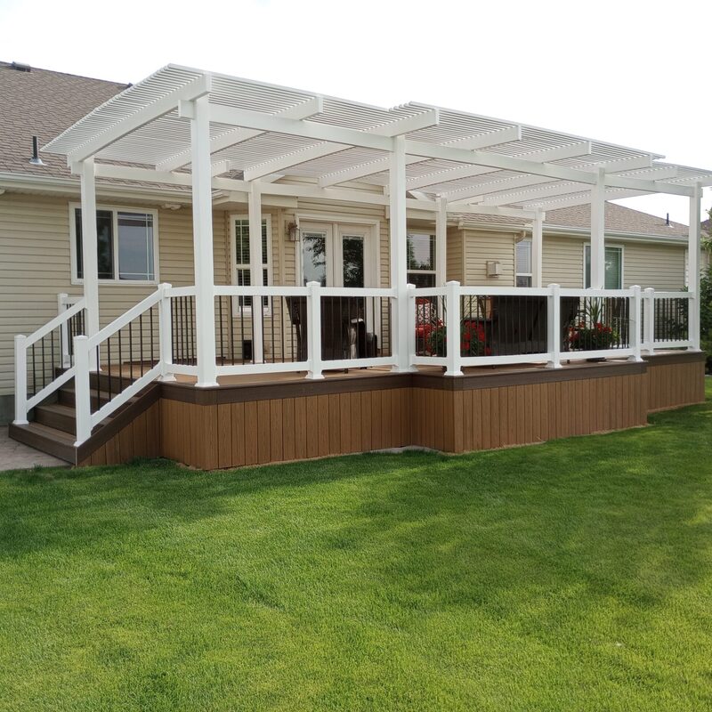Create a stunning and functional backyard oasis with a custom composite deck and pergola from DeckPro LLC. This project features durable brown composite decking and skirting, perfectly complemented by a large white vinyl pergola for shade. The design is finished with stylish white railings and black metal balusters, offering a perfect blend of beauty and low-maintenance living.