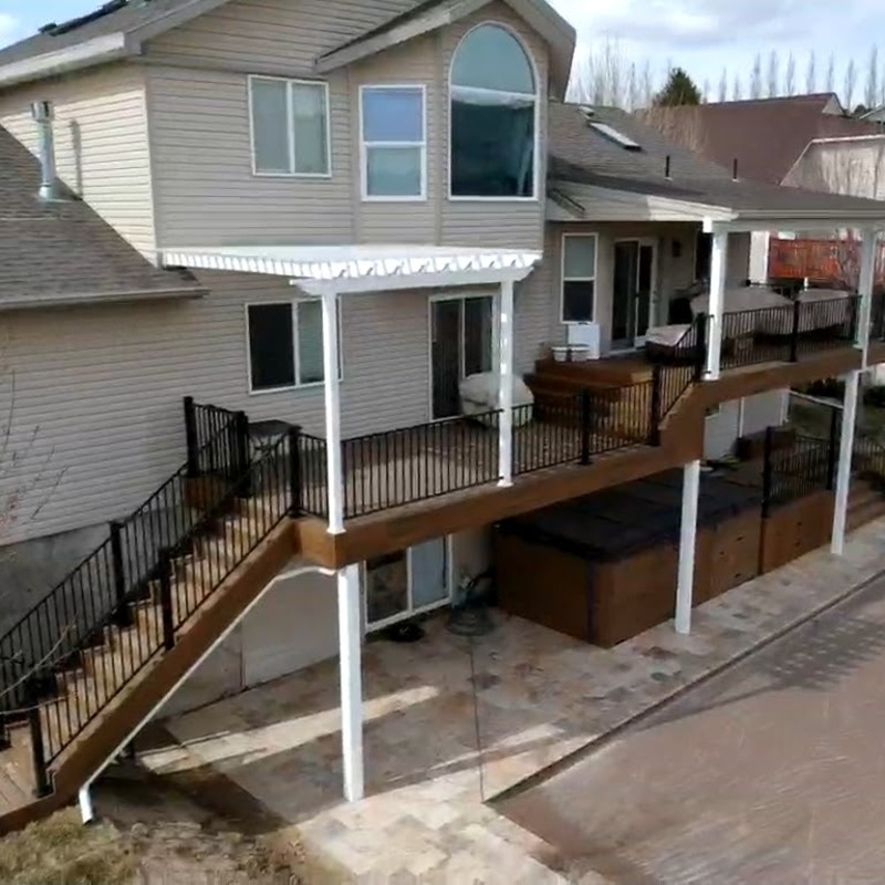 Extend your outdoor living possibilities with this sophisticated composite deck project by DeckPro LLC. We installed durable, low-maintenance composite decking in a warm wood-grain finish, creating a vast and stylish retreat for your backyard. The unique privacy screen system transitions from natural wood components to elegant dark metal balusters, all while including integrated corner privacy panels. For the ultimate in defined functional areas, this build features expansive space for a large conversation set and a complete dining table with patio chairs, perfectly connected by a sturdy staircase to a lower patio. Pictured on a beautiful day with distinct railing shadows, this sturdy design creates a tranquil sanctuary perfect for relaxation and large-scale entertaining.